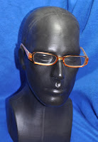 photo of orange reader glasses on a black plastic head