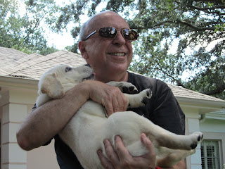 Mr. Merluzzi holding Jam upside down in his arms while Jam tries to lick his face. Mr. Merluzzi holding Jam upside down in his arms while Jam tries to lick his face.