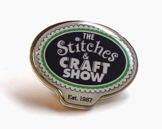 Rounded enamelled badge with the rounded logo which says "The Stitches & CRAFT SHOW Est. 1987"