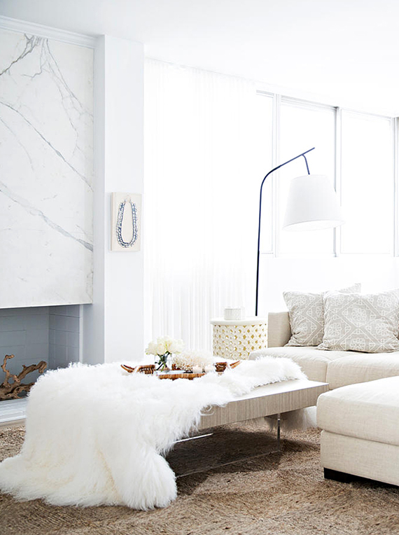 Chic living room in pure whites and a gorgeous marble fireplace. Image by Brittany Ambridge via Domino