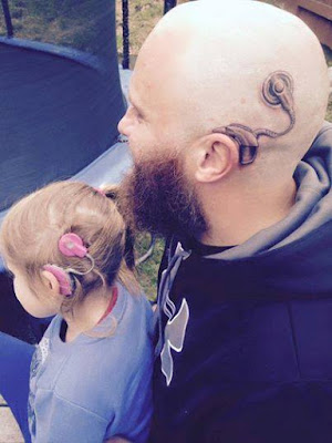 Man and girl facing away from camera, man with shaved head and tattoo of choclear implant