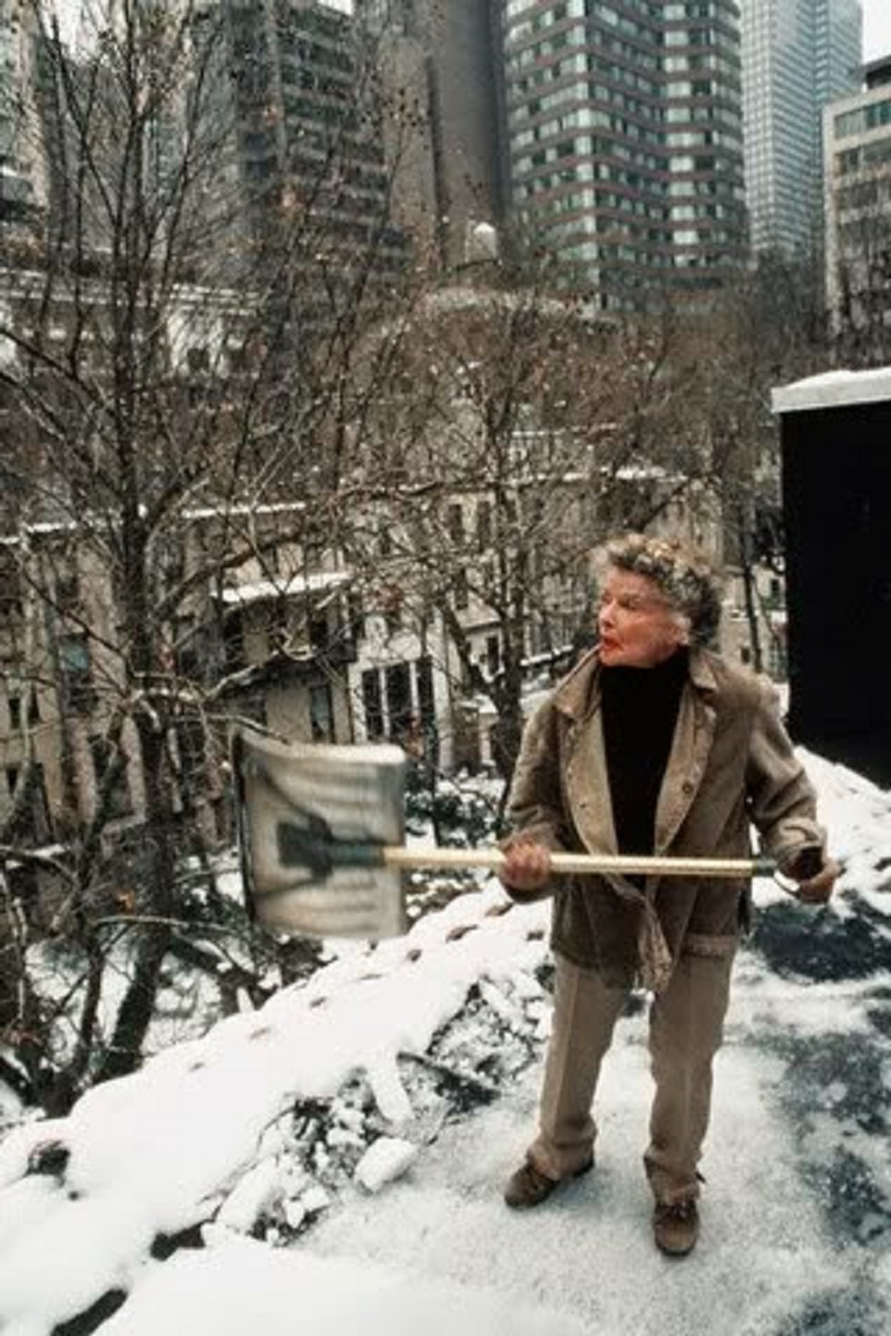 Turtle Bay in the winter, Hepburn shovelling snow off the roof of her city home so it won't leak.