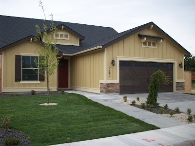 CBH Homes image of a front yard and driveway/entryway of a house. This house is a a one-story, two-car garage house with mustard colored exterior paint.