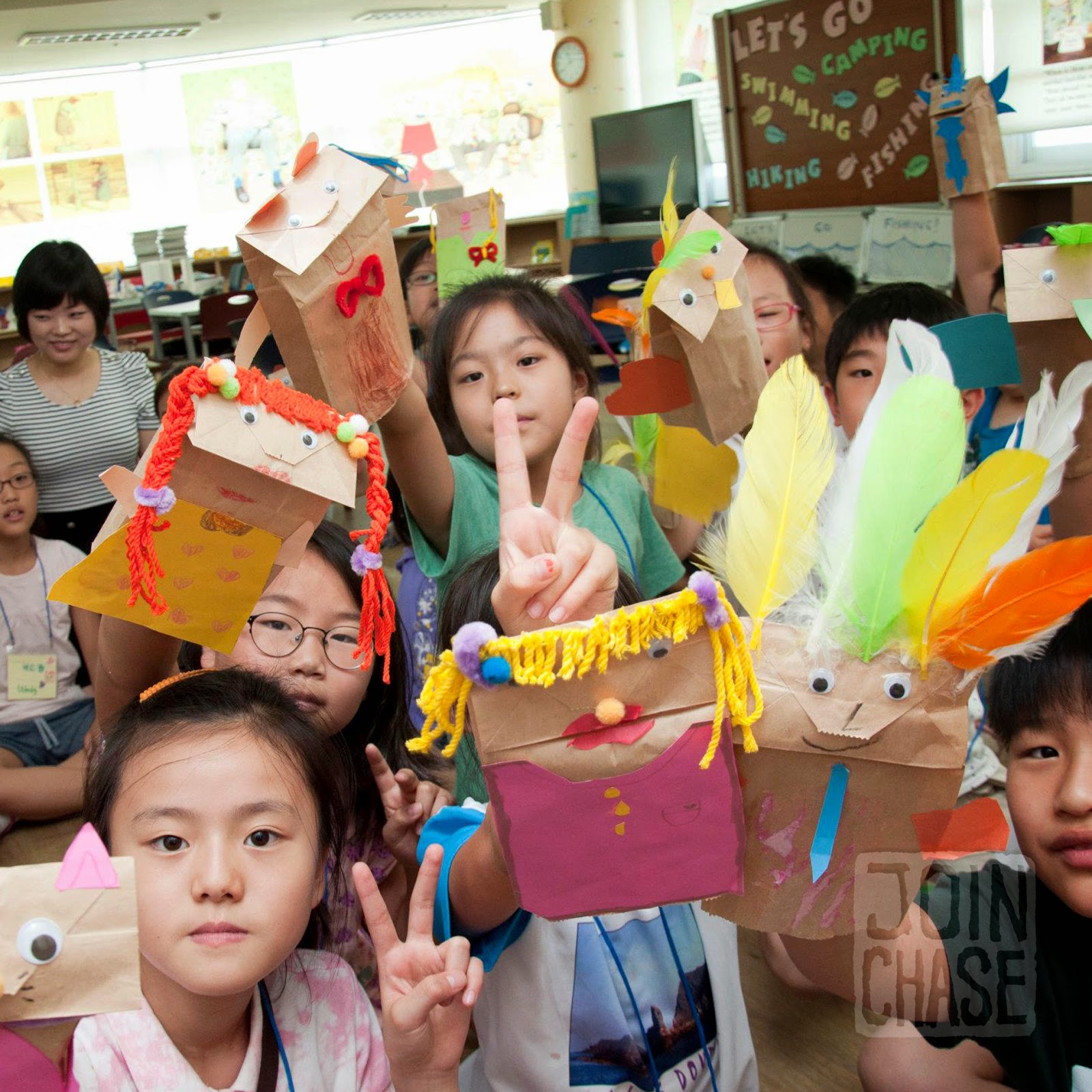 Korean elementary students showing paper bag puppets they made at an English camp in South Korea.