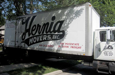 White truck with large script lettering Hernia Movers