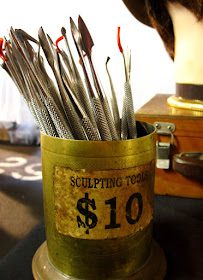 A container of sculpting tools for sale on a market stall.