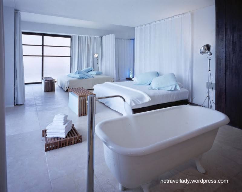 Espacios privados sin divisiones forman un gran ambiente blanco y luminoso Dormitorio doble con bañera al piso con patas