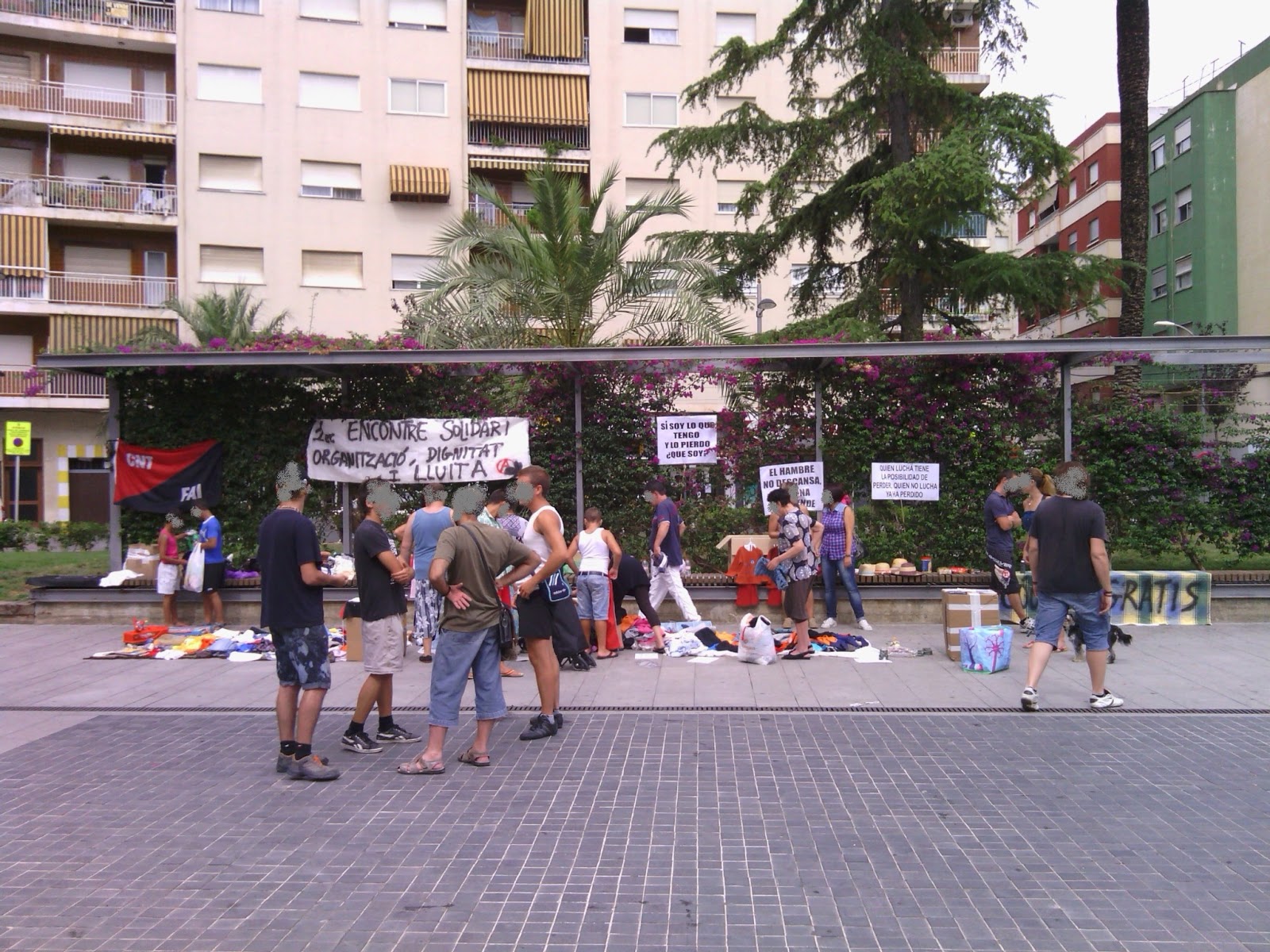 CRÓNICA DEL 1er ENCUENTRO SOLIDARIO Tras unas semanas de trabajo y esfuerzo de los compañeros y compañeras, quedaban ya unas pocas horas para empezar con el Encuentro Solidario organizado desde CNT-La Safor, el grupo anarquista Camilo Berneri, de la FAI, y el grupo anarquista Los Solidarios. Habíamos recogido ropa, material escolar, libros, comida y diferentes enseres como algún juguete o gatos para automóvil. También teníamos a punto diferentes panfletos, folletos y pancartas. En efecto, finalmente teníamos con qué empezar y dar impulso a la jornada, pero aun así sabíamos que nos dejábamos muchas cosas pendientes. Sin embargo este primer encuentro sería solamente el pistoletazo de salida, el primer paso del largo camino sobre el que deberemos actuar, reflexionar, y corregir si hiciese falta antes de volver a dar el siguiente paso. Hacia bien entrado el mediodía del viernes, a menos de 24 horas del encuentro el ayuntamiento advirtió a una de las compañeras que no iba a consentir que nos emplazáramos en el lugar elegido para llevar a cabo esta jornada. Pero como su ley no es justicia ni ley natural, sino autoritarismo y exterminio, tampoco íbamos a hacer caso de los balidos del alcalde y su manada. De todas maneras, siendo poco más de las ocho de la mañana del sábado, no sabíamos con qué íbamos a encontrarnos y las dudas corroían nuestras mentes… ¿la jornada tendría unos resultados satisfactorios? ¿comprendería el barrio qué estábamos haciendo y por qué? ¿cómo lo aceptarían? Llegó el momento y llegamos a la plaza Elíptica para desplegar todos los bultos y cajas que traíamos. La bandera rojinegra observaba expectante cómo íbamos distribuyendo la ropa, los zapatos, los folletos, los libros… Gandía aún estaba terminando de despertar y sus calles a duras penas eran invadidas por unos pocos pares de pies que paseaban apresurados. Y llegó el primer vecino, un hombre que terminaba su jornada de trabajo como celador y que, a sabiendas del encuentro, se acercó a traer una bolsa con comida sin llevarse nada a cambio. Poco a poco iba acercándose más gente. Se sorprendían al ver ropa nueva con etiquetas (una tienda de ropa que cerró nos donó una importante cantidad de ropa infantil y adulta sin estrenar). “¿Cuánto cuesta ésto?”, preguntaba algún despistado o despistada. Había carteles que describían el sencillo funcionamiento del encuentro: “coge lo que necesites”, y a quien pudiere, “trae lo que puedas”, pero la próxima vez lo pondremos más grande y más claro. Otra niña se llevó unos libros de secundaria y al poco rato volvió para traer los que ella ya había usado anteriormente para poder compartirlos. Otros chicos bajaron cargados con cajas y bolsas, y se iban formando pequeños corrillos de gente que, entre agradecimientos, comentarios y razonamientos, medio llenaban esta zona de la plaza. En medio de este ambiente fraternal y solidario llegaron compañeros de la CNT de los sindicatos de Sagunto, Albaida y Valencia, y la alegría se multiplicó. Estos compañeros recorrieron distancias considerables con el llano y noble objetivo de echarnos una mano, es decir, de currar toda la mañana junto con nosotras y nosotros. En esos momentos es cuando verdaderamente me llena de orgullo y emoción pertenecer a la CNT. Todas las dudas que albergábamos en las primeras horas del día se fueron disipando a medida que avanzaba la mañana. Los resultados fueron mucho mejores de lo esperados: muchas familias humildes del barrio se pudieron beneficiar de esta jornada además de empezar a establecer lazos de simpatía y solidaridad entre todos y todas las presentes; otras familias también ejercieron esta solidaridad al compartir aquello que bienintencionadamente podían; y hubo otras personas que se interesaron por la faceta ideológica del encuentro, llevándose algunos folletos y preguntando sobre algunos aspectos de la situación actual y el punto de vista libertario. Algún anciano desmemoriado, porque enterró la memoria y no porque la perdió, pasó refunfuñando que hacían falta tres Franco y un Hitler para limpiarlo todo de tanto sinvergüenza. No le dimos mayor importancia de la que tiene mirar cómo defeca un cerdo. Luego llegó una pareja de policías rebuznando que unos vecinos se habían quejado y nos instaron primero a marcharnos, y ante la negativa, a quitar las pancartas (que rezaban oraciones como “Rodrigo Rata”), pero finalmente no se movió nada del sitio. Llegó el mediodía y después de estar horas soportando el tórrido sol, que tuvo la osadía de aparecer de entre las nubes a media mañana, empezamos a recoger. La gente empezaba ya a refugiarse en sus casas huyendo del calor y buscando un plato de comida y tal vez una siesta con ventilador, tales son las vacaciones del pobre y del trabajador. Tan grande fue la solidaridad del barrio, que al terminar nos fuimos con más bultos de los que trajimos, así que deberemos repetir esta jornada, evaluando bien la primera experiencia para corregir errores y mejorar en nuestro camino hacia la organización popular desde una perspectiva libertaria. Al terminar las compañeras y compañeros acudimos a un pequeño huerto de uno de los compañeros del sindicato local y, en un pequeño oasis que una sombra de un cobertizo de cañas formaba en medio del campo, degustamos una sabrosa paella echa a leña, culminando la jornada entre conversaciones cómicas y debates serios, entre recuerdos pasados e ilusiones futuras, y todo ello inmerso en un fraternal y cálido ambiente refrescado por la brisa marina del litoral gandiense. Ante todo lo expuesto, repetiremos esta jornada, no quepa duda, habiendo localizado algunos aspectos que deberemos mejorar. El siguiente encuentro terminará de consolidar lazos entre el vecindario, haciendo cada vez más posible una organización popular. Nosotros, los anarquistas, estamos al lado del pueblo para luchar contra los ataques que a todos nos impiden vivir dignamente y en plena libertad, no estamos a su lado para decirles cómo deben de actuar. Nunca podremos llevar a cabo una Revolución Social Libertaria sin el levantamiento del pueblo, y el pueblo no puede defender la causa libertaria si no sabe en qué consiste, qué defiende y por qué lucha. Para gran parte de este pueblo, las y los anarquistas aún somos los vagos, los maleantes, violentos y terroristas, quienes queremos que todo sea de todos para vivir a costa de quienes trabajan, pero nosotras y nosotros sabemos que eso no es en absoluto cierto. La libertad no se piensa, no se explica, no se define… la libertad se siente dentro, impulsa nuestro corazón y dirige los movimientos de nuestro cuerpo. Y si no contagiamos al pueblo este sentimiento de libertad nos veremos destinados a vivir a sus espaldas y bajo el yugo común del Estado. Sí, ahora sí que no tenemos duda alguna: el segundo encuentro será mucho mejor, y por supuesto ampliaremos los objetivos que nos planteemos para esa jornada y, con ello, las acciones que la completarán. Pero no adelantemos acontecimientos. Continuaremos informando sobre este tipo de encuentros. Salud, libertad y Revolución Social. CNT-La Safor Grupo Anarquista Los Solidarios Grupo Anarquista Camilo Berneri – FAI CRÓNICA DEL 1er ENCUENTRO SOLIDARIO Tras unas semanas de trabajo y esfuerzo de los compañeros y compañeras, quedaban ya unas pocas horas para empezar con el Encuentro Solidario organizado desde CNT-La Safor, el grupo anarquista Camilo Berneri, de la FAI, y el grupo anarquista Los Solidarios. Habíamos recogido ropa, material escolar, libros, comida y diferentes enseres como algún juguete o gatos para automóvil. También teníamos a punto diferentes panfletos, folletos y pancartas. En efecto, finalmente teníamos con qué empezar y dar impulso a la jornada, pero aun así sabíamos que nos dejábamos muchas cosas pendientes. Sin embargo este primer encuentro sería solamente el pistoletazo de salida, el primer paso del largo camino sobre el que deberemos actuar, reflexionar, y corregir si hiciese falta antes de volver a dar el siguiente paso. Hacia bien entrado el mediodía del viernes, a menos de 24 horas del encuentro el ayuntamiento advirtió a una de las compañeras que no iba a consentir que nos emplazáramos en el lugar elegido para llevar a cabo esta jornada. Pero como su ley no es justicia ni ley natural, sino autoritarismo y exterminio, tampoco íbamos a hacer caso de los balidos del alcalde y su manada. De todas maneras, siendo poco más de las ocho de la mañana del sábado, no sabíamos con qué íbamos a encontrarnos y las dudas corroían nuestras mentes… ¿la jornada tendría unos resultados satisfactorios? ¿comprendería el barrio qué estábamos haciendo y por qué? ¿cómo lo aceptarían? Llegó el momento y llegamos a la plaza Elíptica para desplegar todos los bultos y cajas que traíamos. La bandera rojinegra observaba expectante cómo íbamos distribuyendo la ropa, los zapatos, los folletos, los libros… Gandía aún estaba terminando de despertar y sus calles a duras penas eran invadidas por unos pocos pares de pies que paseaban apresurados. Y llegó el primer vecino, un hombre que terminaba su jornada de trabajo como celador y que, a sabiendas del encuentro, se acercó a traer una bolsa con comida sin llevarse nada a cambio. Poco a poco iba acercándose más gente. Se sorprendían al ver ropa nueva con etiquetas (una tienda de ropa que cerró nos donó una importante cantidad de ropa infantil y adulta sin estrenar). “¿Cuánto cuesta ésto?”, preguntaba algún despistado o despistada. Había carteles que describían el sencillo funcionamiento del encuentro: “coge lo que necesites”, y a quien pudiere, “trae lo que puedas”, pero la próxima vez lo pondremos más grande y más claro. Otra niña se llevó unos libros de secundaria y al poco rato volvió para traer los que ella ya había usado anteriormente para poder compartirlos. Otros chicos bajaron cargados con cajas y bolsas, y se iban formando pequeños corrillos de gente que, entre agradecimientos, comentarios y razonamientos, medio llenaban esta zona de la plaza. En medio de este ambiente fraternal y solidario llegaron compañeros de la CNT de los sindicatos de Sagunto, Albaida y Valencia, y la alegría se multiplicó. Estos compañeros recorrieron distancias considerables con el llano y noble objetivo de echarnos una mano, es decir, de currar toda la mañana junto con nosotras y nosotros. En esos momentos es cuando verdaderamente me llena de orgullo y emoción pertenecer a la CNT. Todas las dudas que albergábamos en las primeras horas del día se fueron disipando a medida que avanzaba la mañana. Los resultados fueron mucho mejores de lo esperados: muchas familias humildes del barrio se pudieron beneficiar de esta jornada además de empezar a establecer lazos de simpatía y solidaridad entre todos y todas las presentes; otras familias también ejercieron esta solidaridad al compartir aquello que bienintencionadamente podían; y hubo otras personas que se interesaron por la faceta ideológica del encuentro, llevándose algunos folletos y preguntando sobre algunos aspectos de la situación actual y el punto de vista libertario. Algún anciano desmemoriado, porque enterró la memoria y no porque la perdió, pasó refunfuñando que hacían falta tres Franco y un Hitler para limpiarlo todo de tanto sinvergüenza. No le dimos mayor importancia de la que tiene mirar cómo defeca un cerdo. Luego llegó una pareja de policías rebuznando que unos vecinos se habían quejado y nos instaron primero a marcharnos, y ante la negativa, a quitar las pancartas (que rezaban oraciones como “Rodrigo Rata”), pero finalmente no se movió nada del sitio. Llegó el mediodía y después de estar horas soportando el tórrido sol, que tuvo la osadía de aparecer de entre las nubes a media mañana, empezamos a recoger. La gente empezaba ya a refugiarse en sus casas huyendo del calor y buscando un plato de comida y tal vez una siesta con ventilador, tales son las vacaciones del pobre y del trabajador. Tan grande fue la solidaridad del barrio, que al terminar nos fuimos con más bultos de los que trajimos, así que deberemos repetir esta jornada, evaluando bien la primera experiencia para corregir errores y mejorar en nuestro camino hacia la organización popular desde una perspectiva libertaria. Al terminar las compañeras y compañeros acudimos a un pequeño huerto de uno de los compañeros del sindicato local y, en un pequeño oasis que una sombra de un cobertizo de cañas formaba en medio del campo, degustamos una sabrosa paella echa a leña, culminando la jornada entre conversaciones cómicas y debates serios, entre recuerdos pasados e ilusiones futuras, y todo ello inmerso en un fraternal y cálido ambiente refrescado por la brisa marina del litoral gandiense. Ante todo lo expuesto, repetiremos esta jornada, no quepa duda, habiendo localizado algunos aspectos que deberemos mejorar. El siguiente encuentro terminará de consolidar lazos entre el vecindario, haciendo cada vez más posible una organización popular. Nosotros, los anarquistas, estamos al lado del pueblo para luchar contra los ataques que a todos nos impiden vivir dignamente y en plena libertad, no estamos a su lado para decirles cómo deben de actuar. Nunca podremos llevar a cabo una Revolución Social Libertaria sin el levantamiento del pueblo, y el pueblo no puede defender la causa libertaria si no sabe en qué consiste, qué defiende y por qué lucha. Para gran parte de este pueblo, las y los anarquistas aún somos los vagos, los maleantes, violentos y terroristas, quienes queremos que todo sea de todos para vivir a costa de quienes trabajan, pero nosotras y nosotros sabemos que eso no es en absoluto cierto. La libertad no se piensa, no se explica, no se define… la libertad se siente dentro, impulsa nuestro corazón y dirige los movimientos de nuestro cuerpo. Y si no contagiamos al pueblo este sentimiento de libertad nos veremos destinados a vivir a sus espaldas y bajo el yugo común del Estado. Sí, ahora sí que no tenemos duda alguna: el segundo encuentro será mucho mejor, y por supuesto ampliaremos los objetivos que nos planteemos para esa jornada y, con ello, las acciones que la completarán. Pero no adelantemos acontecimientos. Continuaremos informando sobre este tipo de encuentros. Salud, libertad y Revolución Social. CNT-La Safor Grupo Anarquista Los Solidarios Grupo Anarquista Camilo Berneri – FAI
