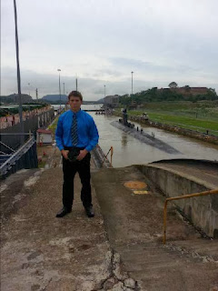 Intern Caleb Lenard poses with a submarine moving through the Panama Canal.