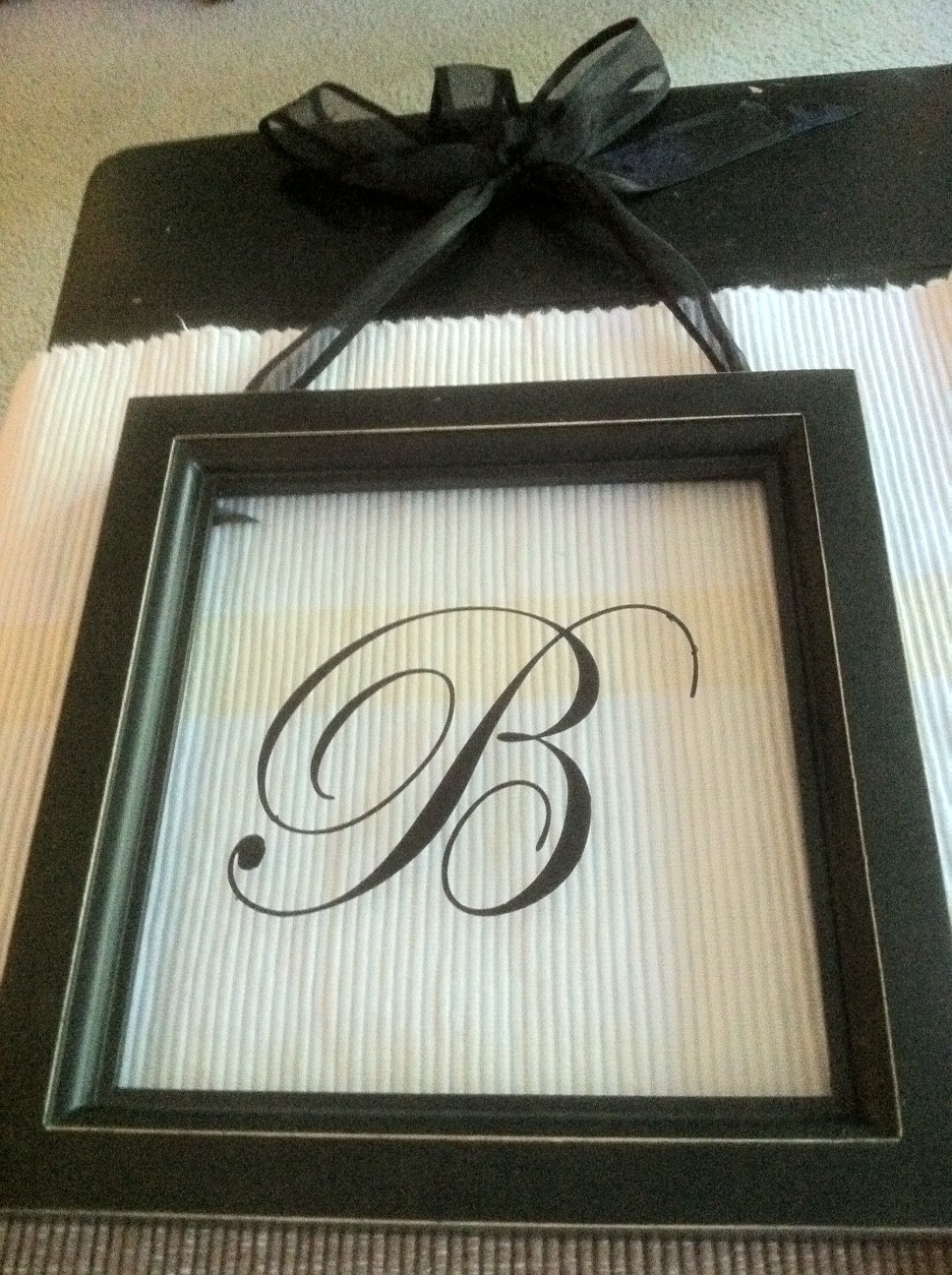 a wee Meenit Monogram Vinyl letter behind glass frame
