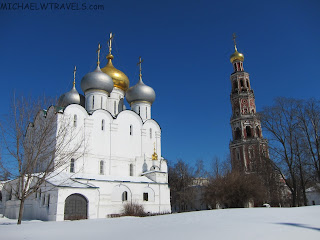 a white building with gold domes and a tower in the background