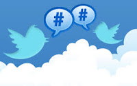 Illustration of two Twitter logo bird facing each other above clouds, with talk balloons containing hashtag symbols