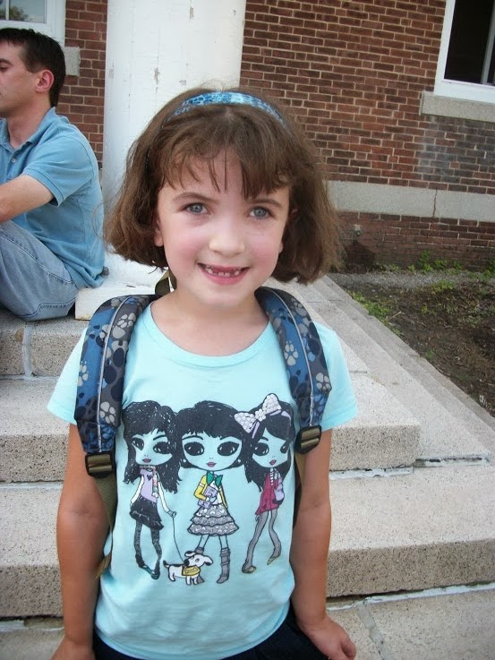 girl with brown hair. blue shirt and a big smile.