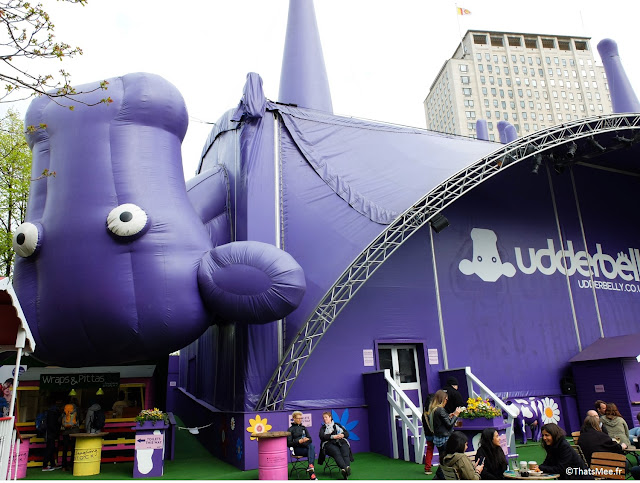 Terrasse du Udderbelly Festival d'art scénique cirque circus shows performance Londres South Bank Center, structure grosse vache violette à l'envres 4 pattes en l'air Londres South Bank, London big purple cow festival