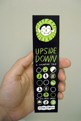 Hand holding GotPrint printed green and black bookmark, "upside down" comic book