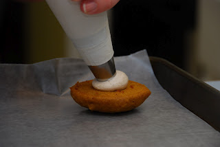 filling being piped onto cookie sandwich half on baking tray