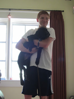 Austin holds Coach as Coach's legs dangle down like an octopus's. Austin holds Coach as Coach's legs dangle down like an octopus's.