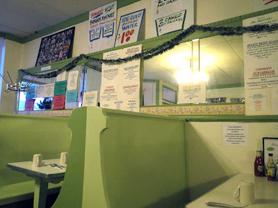 Interior shot of Bonnie's Cafe with light green painted booths and mirrored walls, lots of signs hanging