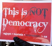 sign saying, This is not democracy. Egypt then Tunisia then Wisconsin then US