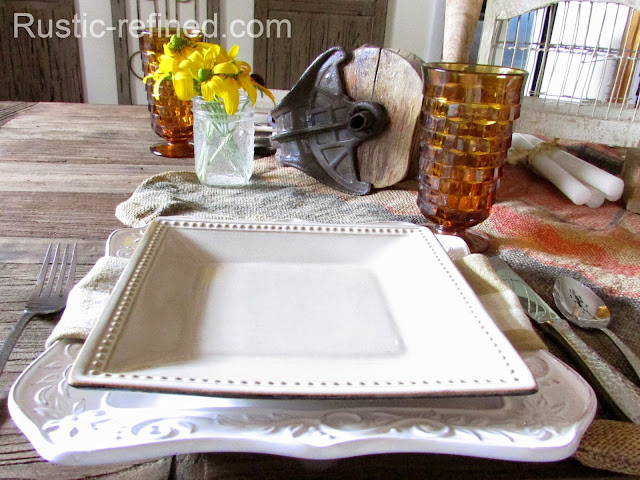 Simple rustic tablescape using wood tone colors white dishes and amber colored glasses.