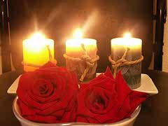 Tres velas encendidas, con dos rosas rojas.