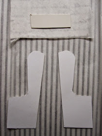 Two cardboard chair component shapes laid out on the wrong side of fabric, ready to be cut out.