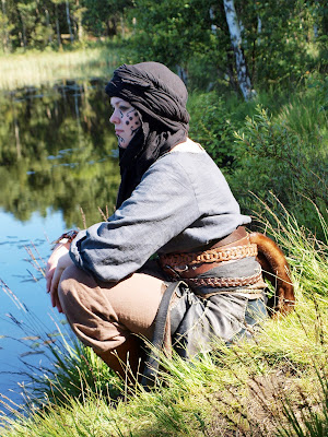 Woman larper resting by a lake.