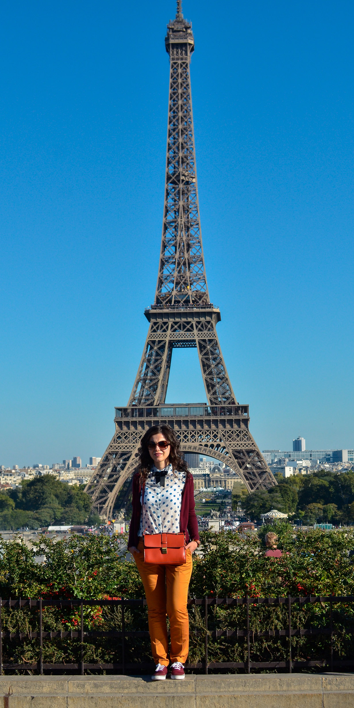 preppy fall outfit in Paris mustard pants burgundy sweater sneakers H&M orange satchel bag dotted shirt blue dots black bow tie champs elysees jardin de tuileries eiffel tower