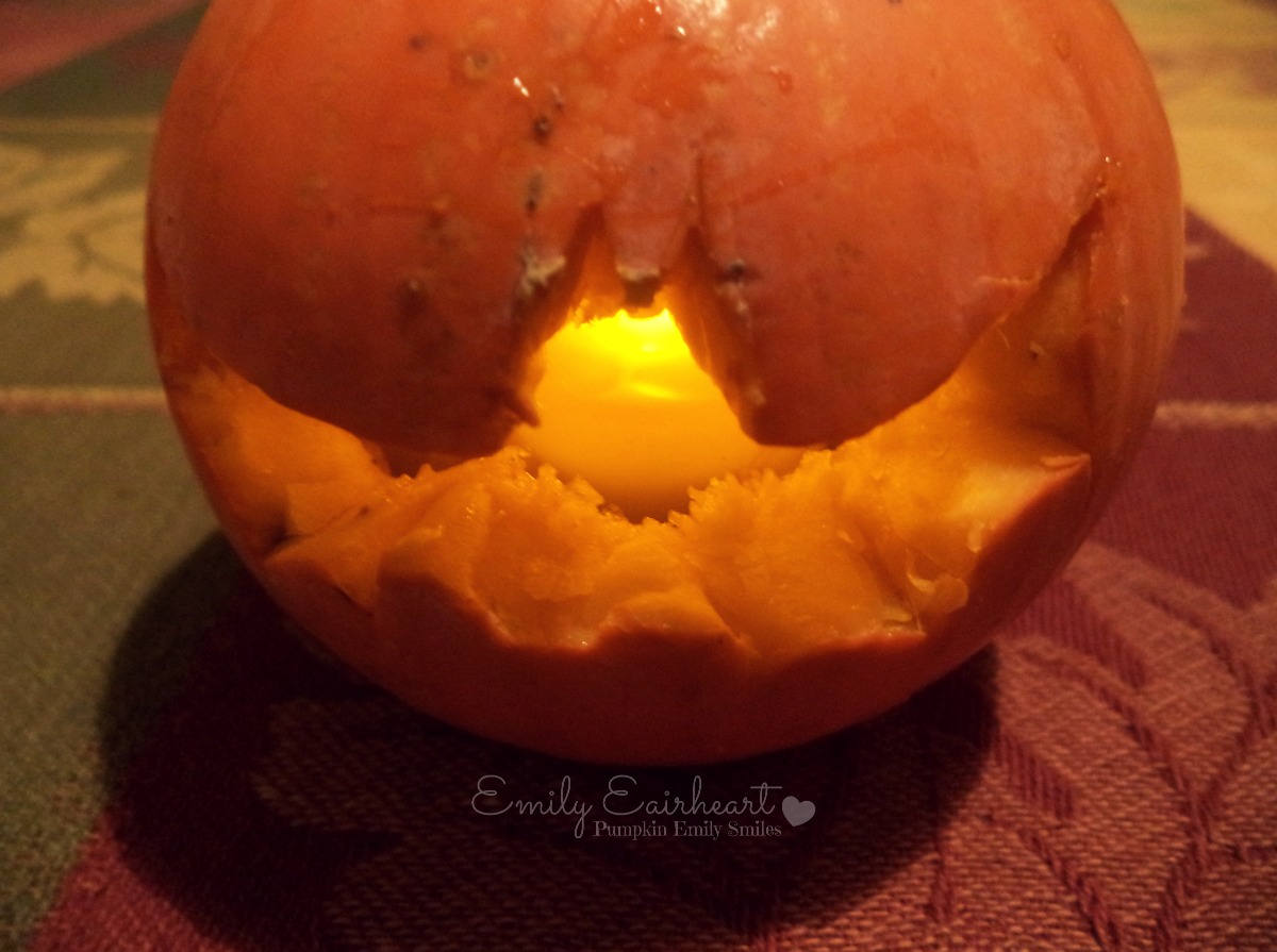 A pumpkin with a carved bat and a candle inside it.