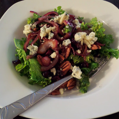Warm Kale Salad:  A salad made of red onions sauteed in oil and balsamic vinegar mixed with kale and topped with blue cheese, toasted pecans, and dried cranberries.