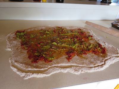 Whole wheat dough covered in pesto and sun dried tomatoes 