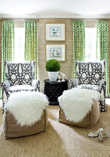 Living room with two sea grass ikat armchairs, woven sea grass sisal rug, green graphic curtains and two large ottomans covered with a furry throw