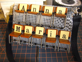 Name tag made from vintage miniature chairs sewn onto plastic canvas with vintage game letters attached to the seats,