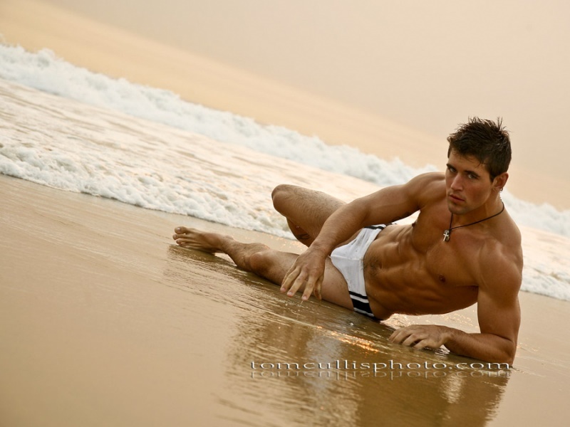 На фото красивый голый парень в пляжном домике