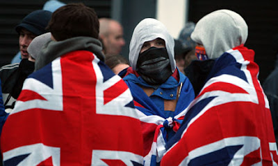 Protesters with covered faces object to the removal of the Union flag from Belfast City Hall