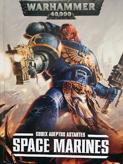 Codex Space Marines front cover. A red helmeted space marine with a chain sword and bolt pistol glowers at his target while striking a dramatic pose
