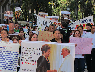 Manifestação em Curitiba (PR) contra a aprovação do PLC 3/2013 (a nova lei do aborto no Brasil. No 1º cartaz os dizeres: A mesma mão que apertou a mão do Papa assinou Projeto favorecendo o aborto! Manifestação em Curitiba (PR) contra a aprovação do PLC 3/2013 (a nova lei do aborto no Brasil. No 1º cartaz os dizeres: A mesma mão que apertou a mão do Papa assinou Projeto favorecendo o aborto!