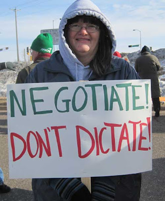 Woman with a sign reading Negotiate! Don't Dictate!