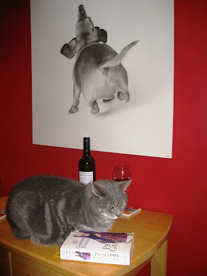 Cat on table with book and wine glass