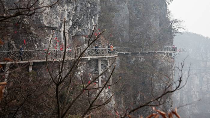 Skywalk On Tianmen Mountain — China Jutting out from a sheer cliff 1,430 meters high, the glass skywalk in Zhangjiajie National Forest Park offers sightseers terrifying thrills and clear view of the mountains below as they tread nervously across the 60 meter long bridge encircling the vertical cliffs of Tianmen Mountain in Hunan province. The 3ft-wide, 2.5in thick glass walkway is so scary that sightseers are requested to wear cloth slip-ons over their shoes when they cross the skywalk, presumably to make the job easier for the cleaners.