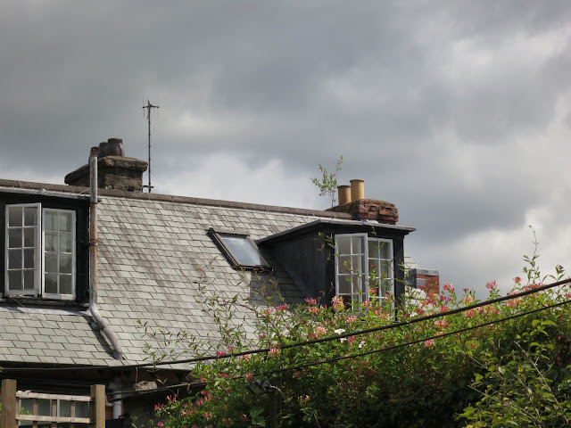 Grey tiled roof, casement windows, honeysuckle, grey sky.