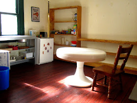 Interior of a modern miniature holiday house kitchen, with a round white table in the foreground.