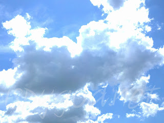 cumulus clouds with bright blue sky backdrop, lined with the sun's brightness