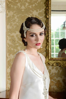 Flapper girl in a 1920's style drop waist bridal gown with a pearl hairband, marcel waves in her hair and 1920's style makeup
