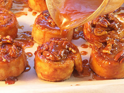 banana sticky buns in pan with caramel being poured over top