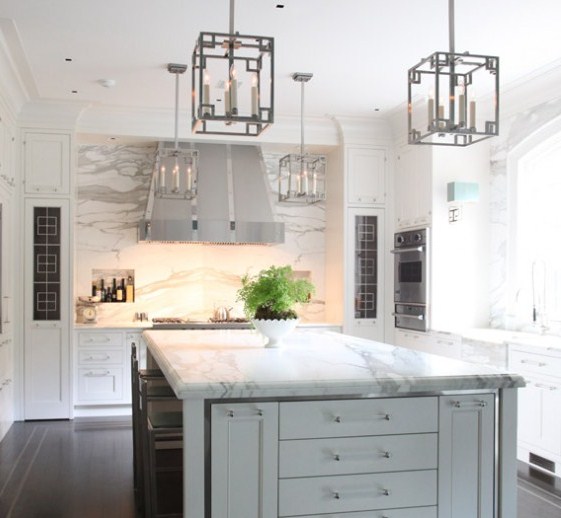 kitchen with marble cabinets, an island, detailed upper cabinetry, a stainless hood and lantern pendant lights