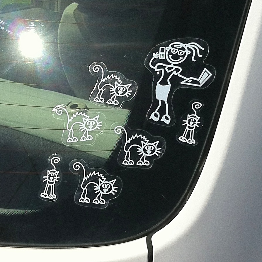 A car's rear window, with six cat stickers surrounding a lady sticker.