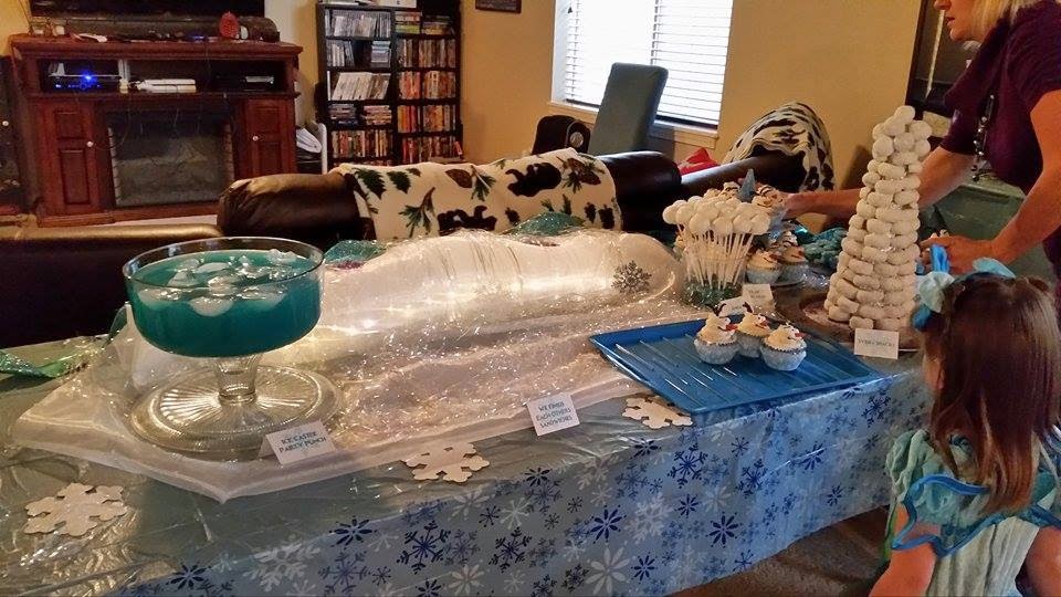 Frozen Birthday Party: Setting up the table--a snowflake table cloth, pretty organza and battery operated lights with iridescent tinsel make a pretty backdrop. table prep