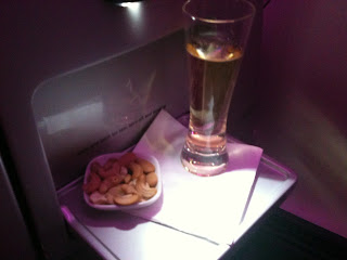 a glass of beer and a bowl of cashews on a tray