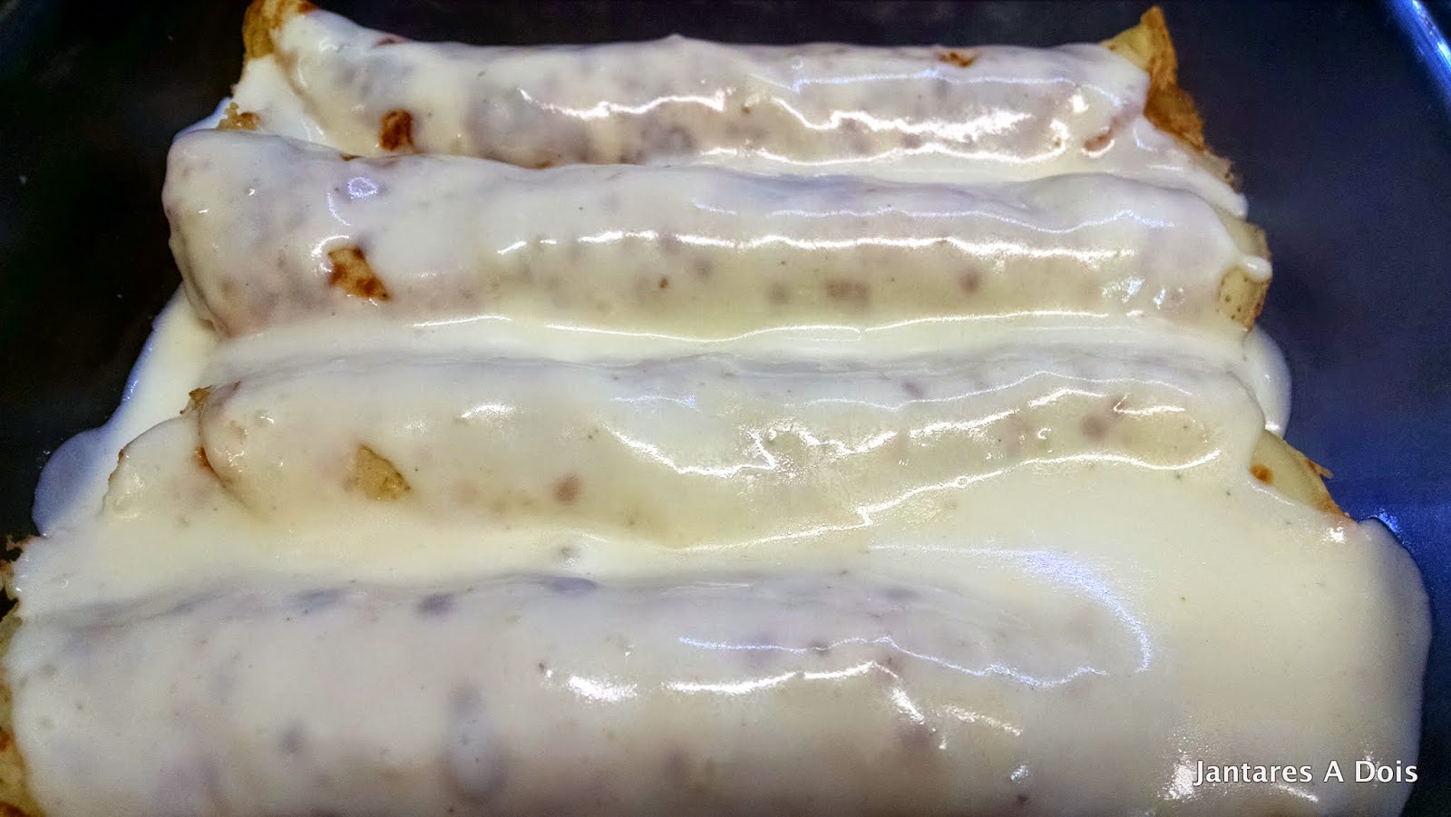 Montagem no prato antes de ir ao forno Panquecas enroladas cobertas com o molho bechamel